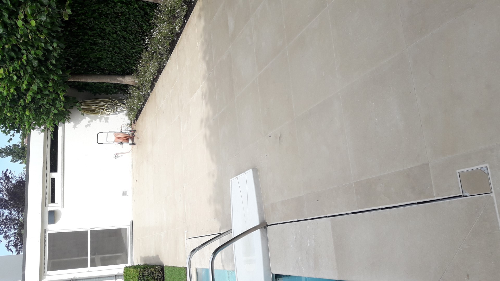 Luxeproject Brugge: Aanleg van terras in Libanese kalksteen met aansluitende zwembadboordstenen. Er zijn verdoken aquadrains ingewerkt in het terras